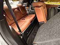 2026-Outlander-PHEV-seating - Two Hills Voice Cargo area of a car with orange-brown leather rear seats folded down, gray carpeting, and a visible seat belt.